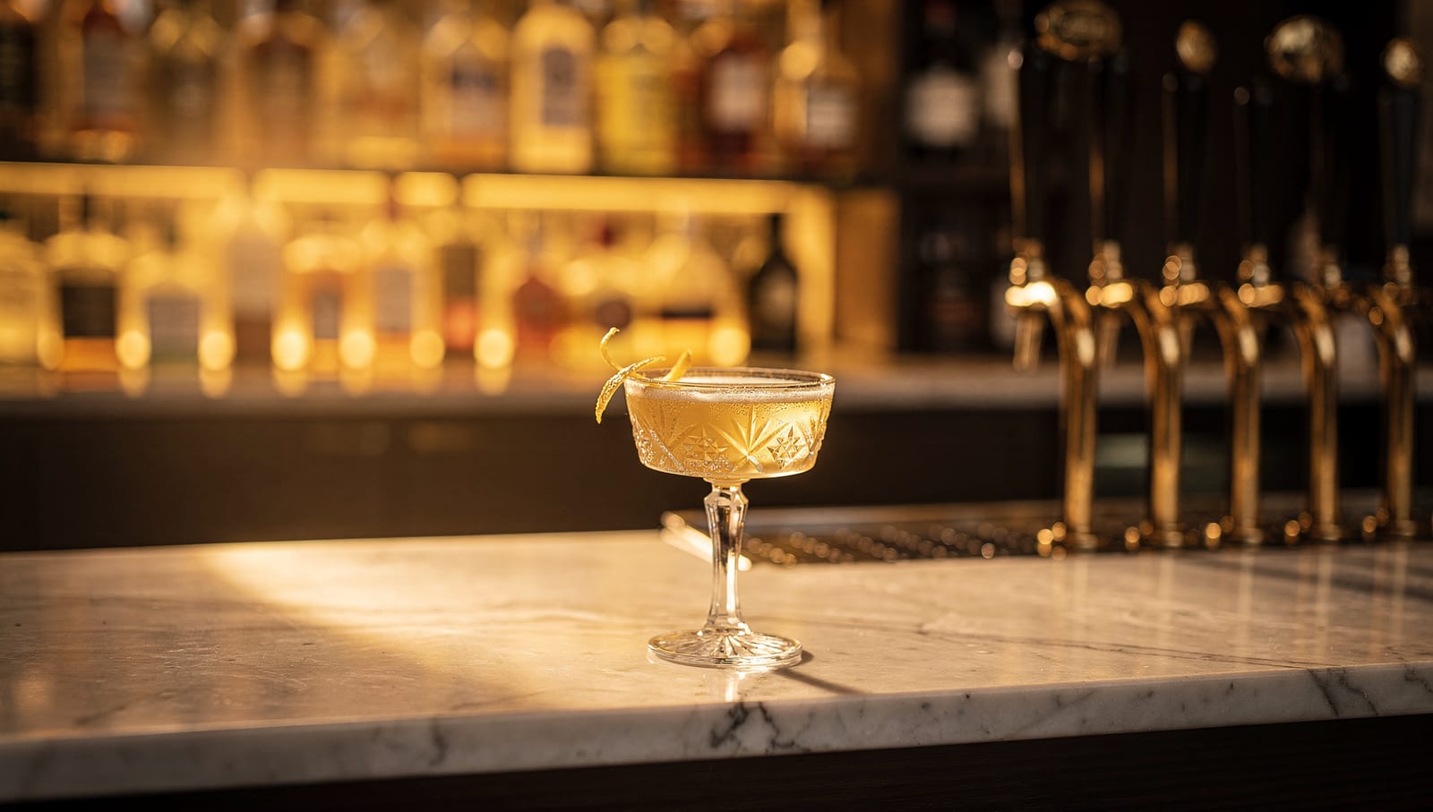 A craft cocktail beside brass taps at the marble bar